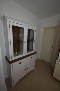 a white cabinet with glasses in it in a room at Ferienwohnung mit Boxspringbett in Behrensdorf