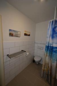 a bathroom with a toilet and a shower curtain at Ferienwohnung mit Boxspringbett in Behrensdorf