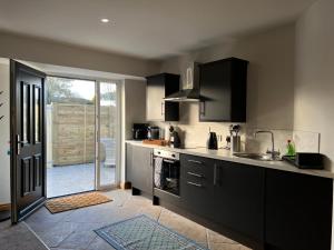 uma cozinha com armários pretos e uma porta aberta em Hunters Glebe Country Apartment em Castlerock
