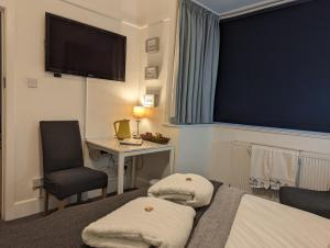 a hotel room with a bed and a desk and a television at En-suite room, fridge microwave TV, great value homestay, near forest & sea in Lymington