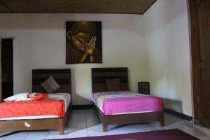 Dos camas en una habitación con un cuadro en la pared. en Shanti Homestay Pacung, en Patjung