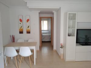 a white dining room with a table and white chairs at Apartamento L' Espumeru in Posada de Llanes