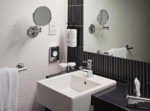 uma casa de banho branca com um lavatório e um espelho em Crowne Plaza Birmingham City, an IHG Hotel em Birmingham