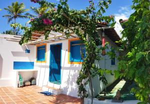 a white house with blue windows and flowers at Cabanas Caraúbas in Maxaranguape