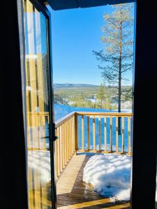 a view from a glass door of a deck with snow at The Riverside Mountain Lodge - 110sqm of Calm Luxury in Idre