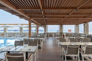 un restaurante con mesas y sillas y una piscina en Caldera Bay en Plataniás