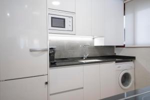 a white kitchen with a washing machine and a microwave at Apartamento-Loft con vistas in Vilafamés
