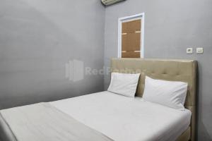 a bedroom with a bed with white sheets and pillows at Puspita Homestay Mitra RedDoorz in Jakarta