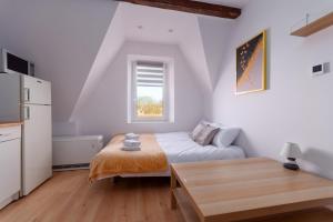 a small white room with a bed and a table at Groszowa Comfort Studio in Jelenia Góra