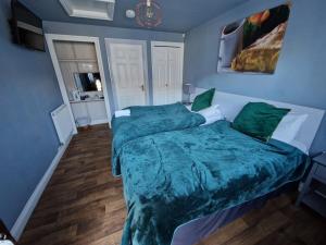 1 dormitorio con 1 cama grande con sábanas verdes en The Farmers Boy Inn Guest House, en Longhope