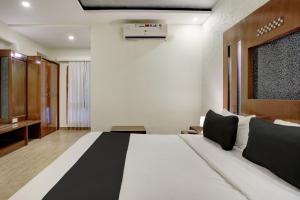 a bedroom with a large white bed and a desk at Super Townhouse Koramangala in Bangalore