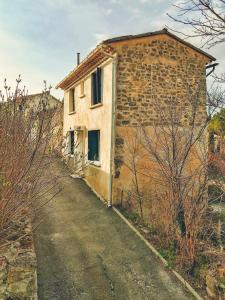 uma velha casa de pedra ao lado de uma estrada em MAISON COSY VENTOUX avec jardin vue Ventoux à Mormoiron em Mormoiron