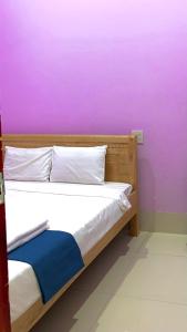 Ce lit se trouve dans un dortoir doté d'un mur violet. dans l'établissement Homestay Châu Triều - Phan Thiết, à Phan Thiết