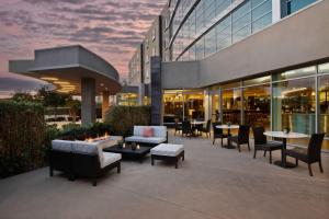 Courtyard by Marriott San Jose North/ Silicon Valley في سان خوسيه: فناء به طاولات وكراسي ومبنى