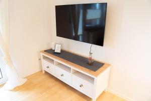 - une commode blanche avec une télévision murale à écran plat dans l'établissement Ferienwohnung Montabaur, à Montabaur