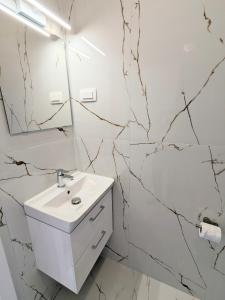 een badkamer met een witte wastafel en marmeren muren bij Metelkova in Ljubljana