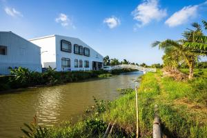 um edifício junto a um rio com uma ponte em VinaEcolife Lodge em Ba Tri