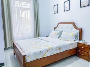 Schlafzimmer mit einem Bett mit einem Holzrahmen und einem Fenster in der Unterkunft Douglas Home in Ruhengeri
