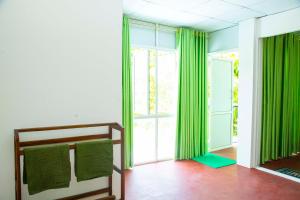 um quarto com cortinas verdes, uma cama e uma janela em Green View Lodge em Deniyaya