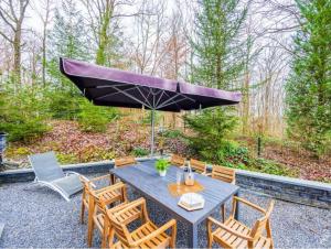 a patio with a table with chairs and an umbrella at Villa Elsa in Durbuy