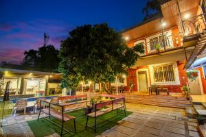 a house with benches in the yard at night at Flora Ecostay Resort and Spa Lonavala in Lonavala