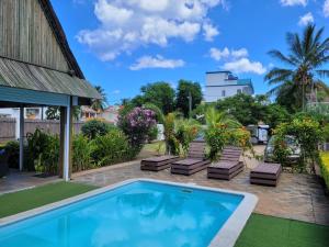 a swimming pool with lounge chairs and a house at Villa Kayana in Flic-en-Flac