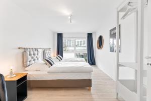 a white bedroom with a bed and a window at Design-Apartment - Küche - Parken - zentral in Leinfelden-Echterdingen