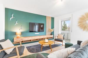 a living room with a couch and a tv on a wall at Design-Apartment - Küche - Parken - zentral in Leinfelden-Echterdingen
