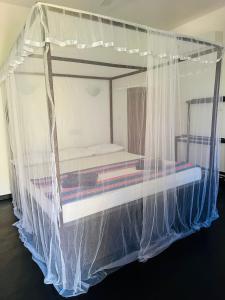 uma cama coberta de redes mosquiteiras num quarto em Lucky Bay em Baía de Arugam