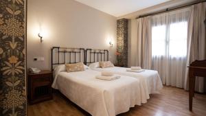 a bedroom with two beds with white sheets and a window at Hospederia Princesa Elima in Brihuega