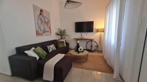 a living room with a black couch and a tv at DION'S HOME with Private Parking at the Center of Kos Town in Kos