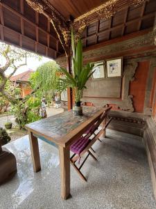 einem Holztisch mit einer Topfpflanze und einer Bank in der Unterkunft Near Ubud, Batuan Homestay Own King Bed Big Room at Royen Balinese Family Guest House in Sukawati