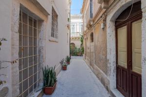 an alley in an old town with potted plants at Giamevi Sicily in Siracusa