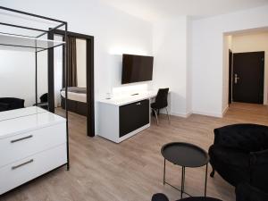 a living room with a bed and a desk with a television at DORMERO Hotel Worms in Worms