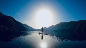 dos personas están de pie en una tabla de paddle en el agua en Kofukaku Kuwarubi, en Fujikawaguchiko