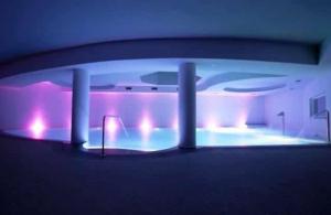 Habitación con una gran piscina con luces moradas. en Bes Hotel Terme di Palazzago en Palazzago
