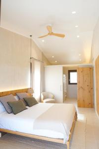 1 dormitorio con 1 cama blanca grande y ventilador de techo en Casa Vinyanova - Only adults, en Fontanilles