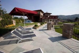 a patio with chairs and an umbrella and a house at Bes Hotel Terme di Palazzago in Palazzago