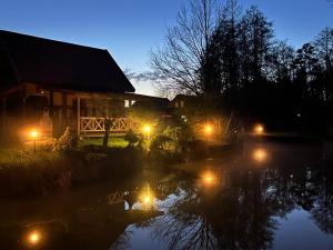 a house with lights in the water at night at Oaza Ławki in Ryn