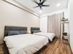 two beds in a room with a ceiling fan at The Cove Hillside Residence Ipoh in Ipoh