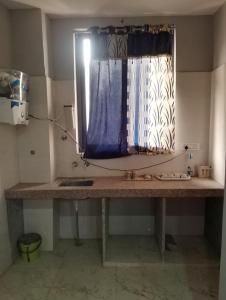 a kitchen counter with a window with a blue curtain at Comfort Inn Guesthouse in Jaipur