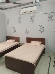 Duas camas num quarto com paredes brancas em Comfort Inn Guesthouse em Jaipur