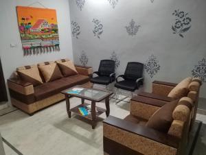 un soggiorno con divani, tavolo e sedie di Comfort Inn Guesthouse a Jaipur