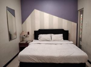 1 dormitorio con 1 cama con pared morada y blanca en Gangnam Style Residence Mitra RedDoorz near MERR Surabaya en Surabaya
