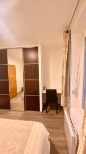 1 dormitorio con cama, silla y espejo en Appt Longwy, très bien situé, en Longwy