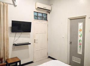 Cette chambre dispose d'une porte blanche, d'une télévision et d'une fenêtre. dans l'établissement Gangnam Style Residence Mitra RedDoorz near MERR Surabaya, à Surabaya