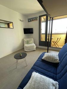 ein Wohnzimmer mit einem blauen Sofa und einem Tisch in der Unterkunft REF 582 Seignosse Océan, à proximité immédiate de la plage , idéal couple in Seignosse
