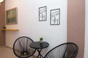 a table and two chairs next to a wall with three paintings at Handakos Loft "by Checkin" in Heraklio