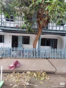een wit gebouw met een wit hek en een boom bij happy angle in Luang Prabang
