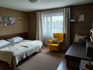 a bedroom with a bed and a chair and a window at Apartmany Adavy in Liptovský Mikuláš